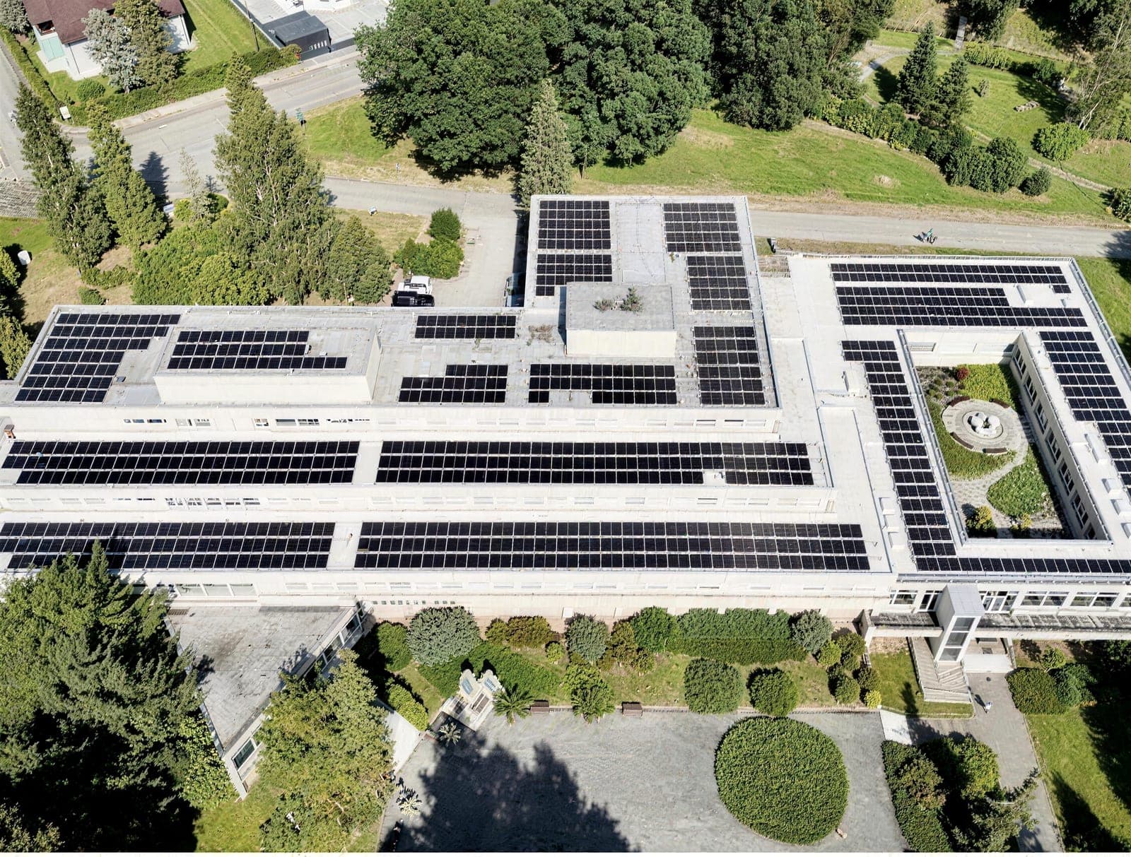 Produktionshalle mit Photovoltaik auf dem Dach inmitten von Grün